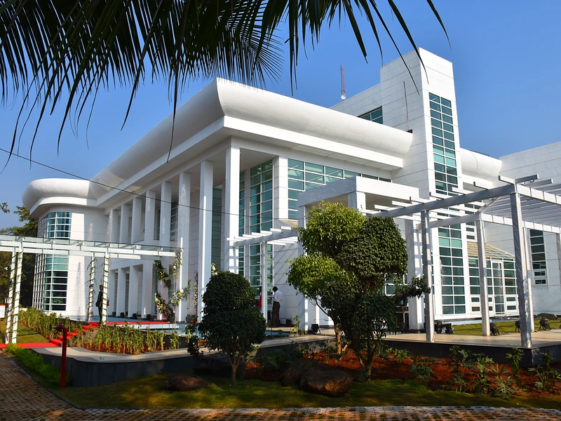 The white facade of AliGunjan framed by palms.